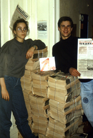 Zwei Jugendliche stehen neben einen Stapel Zeitschriften